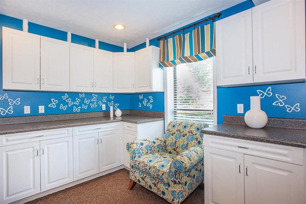 a blue and white kitchen with a chair and white cabinets