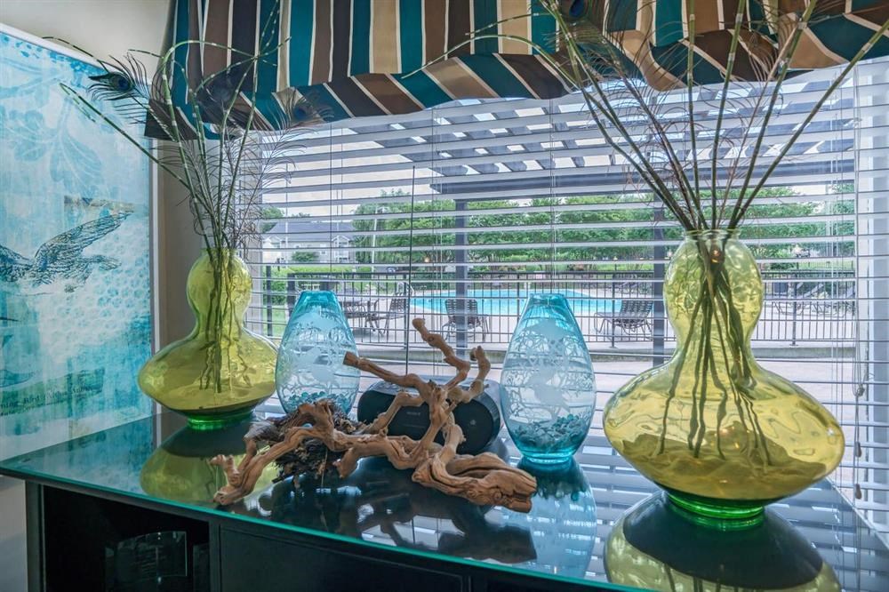 three glass vases sitting on a glass table in front of a window