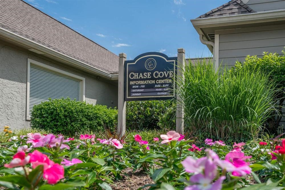 a sign in front of a house with flowers