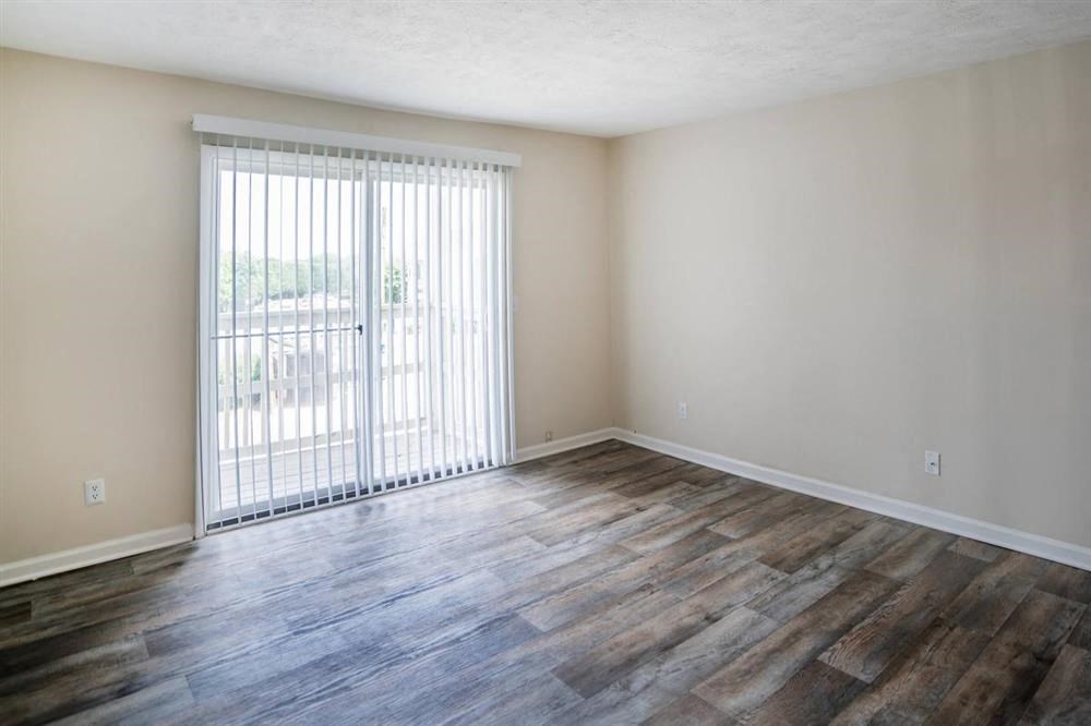 an empty living room with a sliding glass door and wood flooring