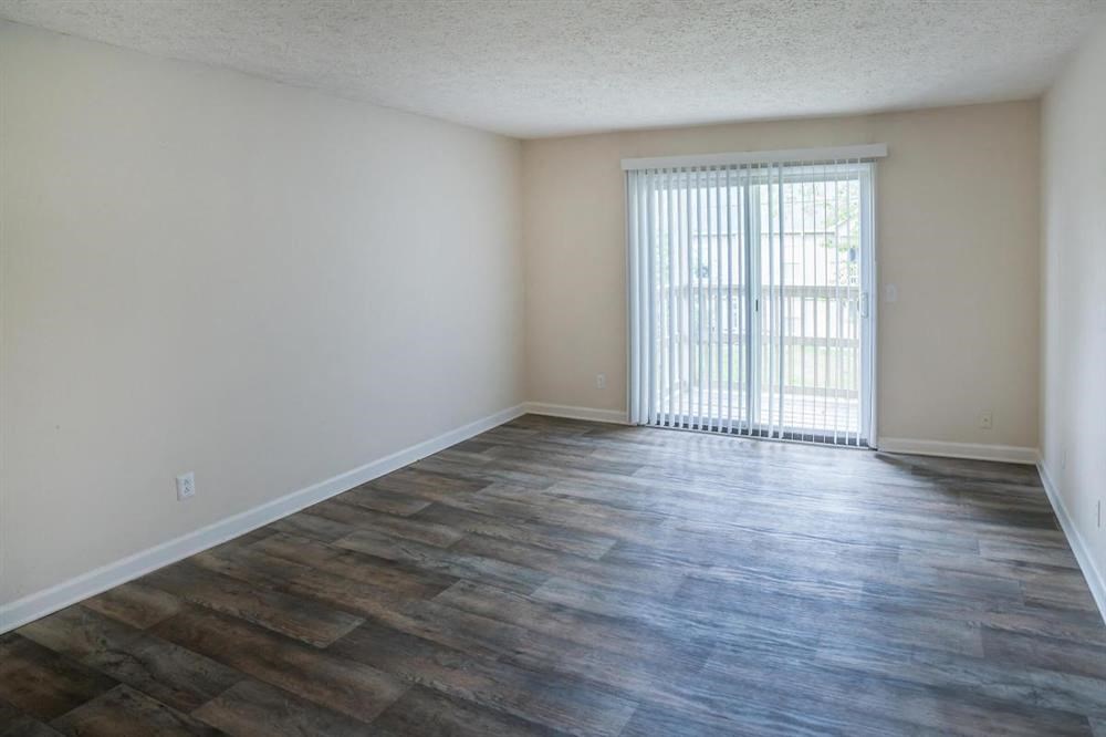 an empty living room with wood floors and a sliding glass door