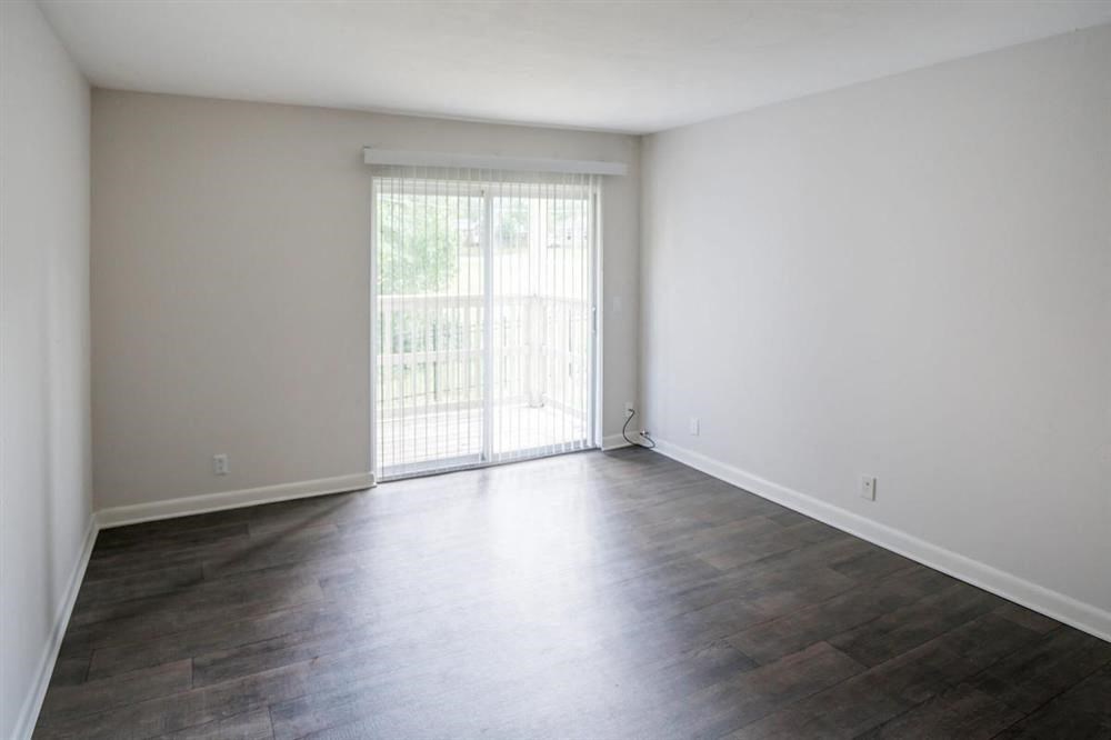 an empty living room with wood floors and a sliding glass door