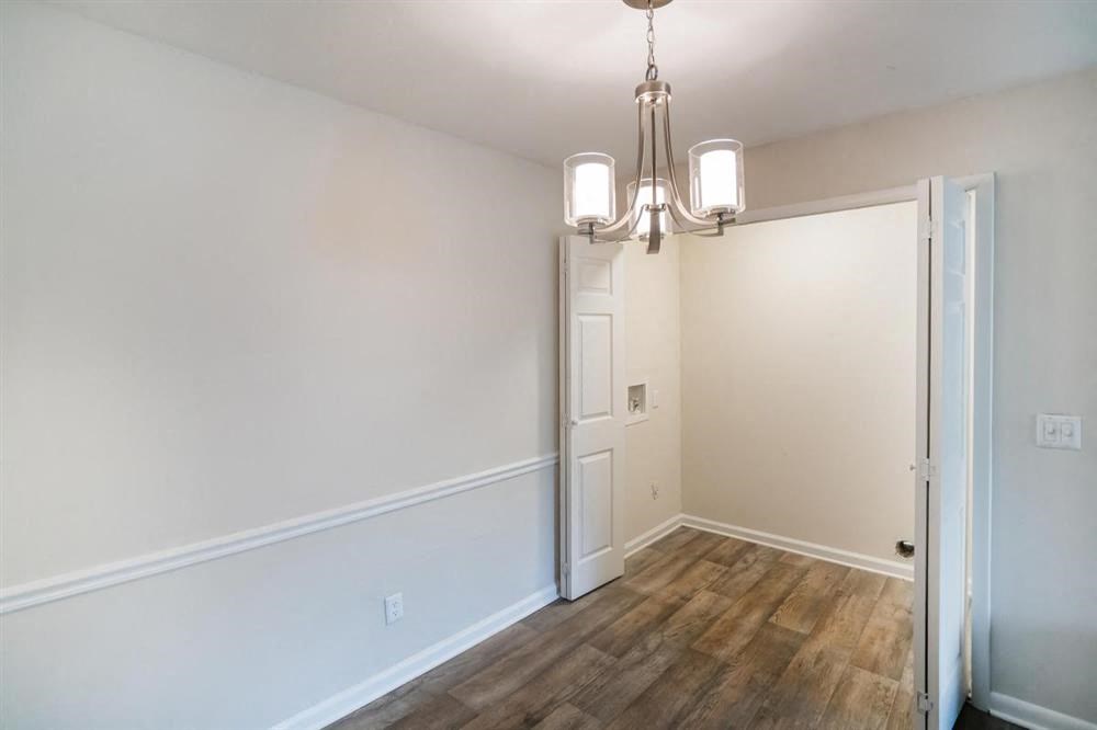 an empty living room with a door and a chandelier