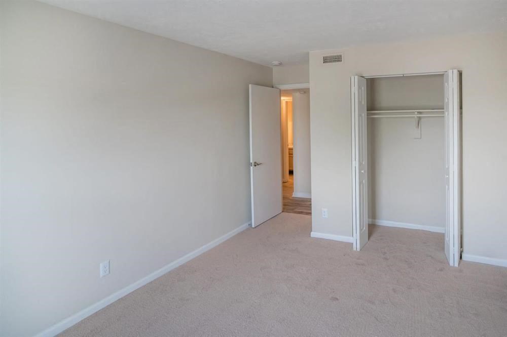 an empty bedroom with a closet and a door to a hallway