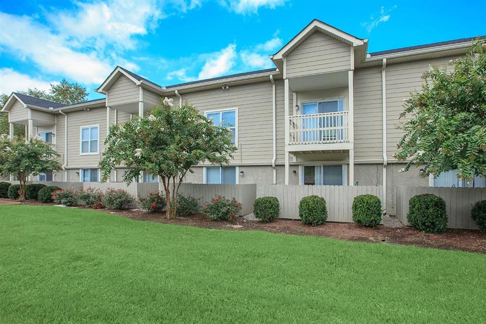 the exterior of an apartment building with green grass and trees