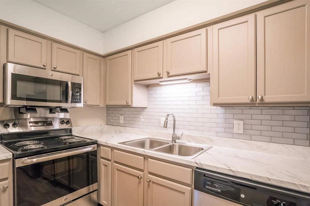 a kitchen with white cabinets and a sink and a microwave