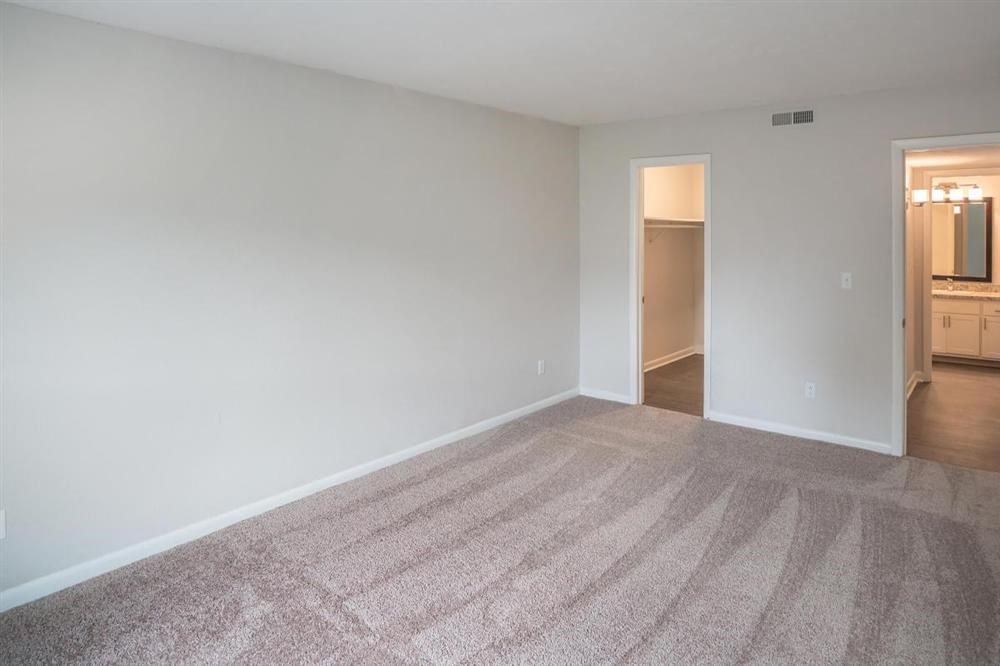 an empty living room with carpet and a door to a kitchen
