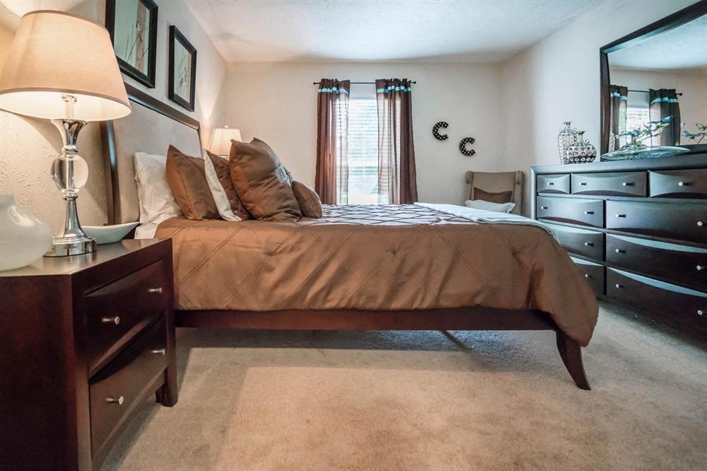 a bedroom with a bed and dresser and a mirror