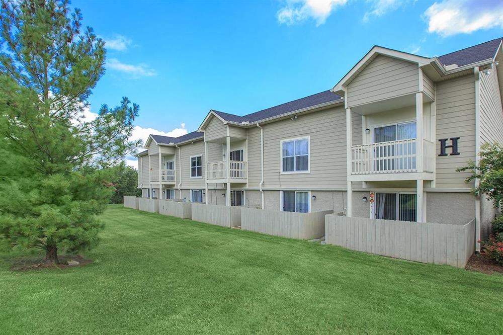 an apartment building with a green lawn and trees