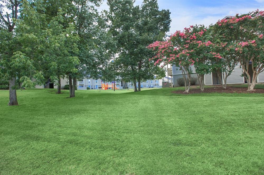 a yard with green grass and trees in front of a building