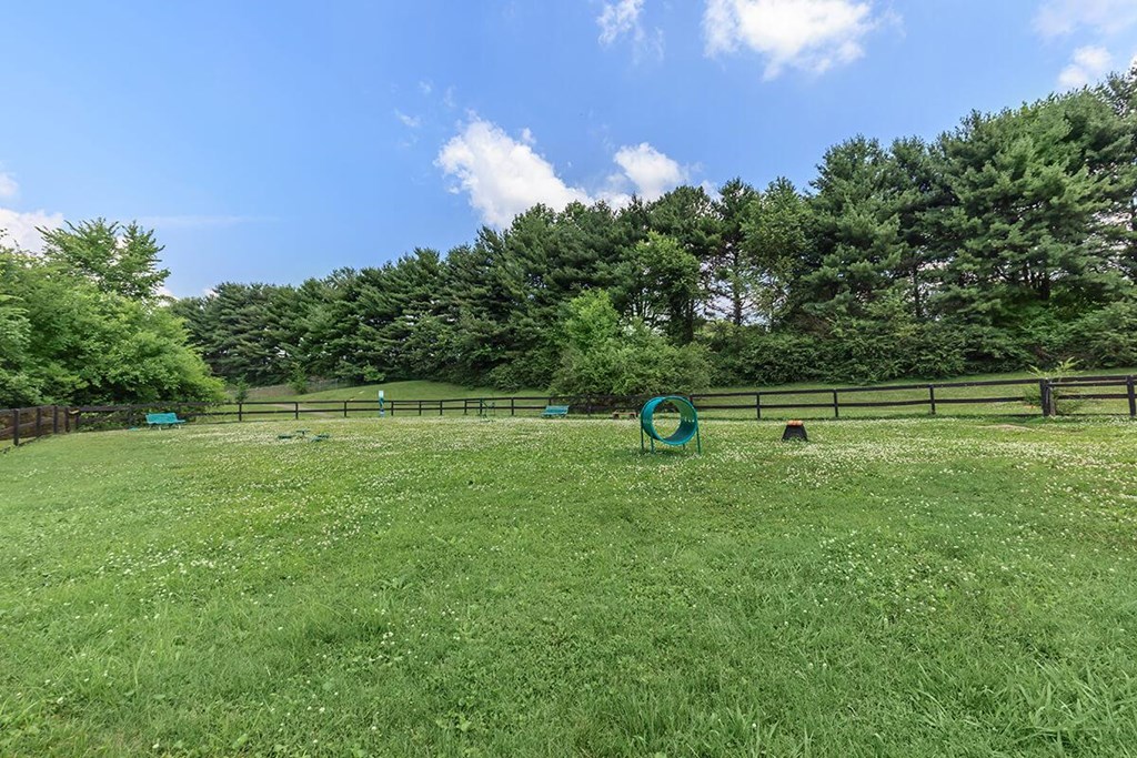 a grassy field with a fence and a sign in the middle