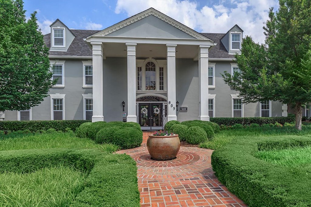 a mansion with a courtyard and a large vase in front of it