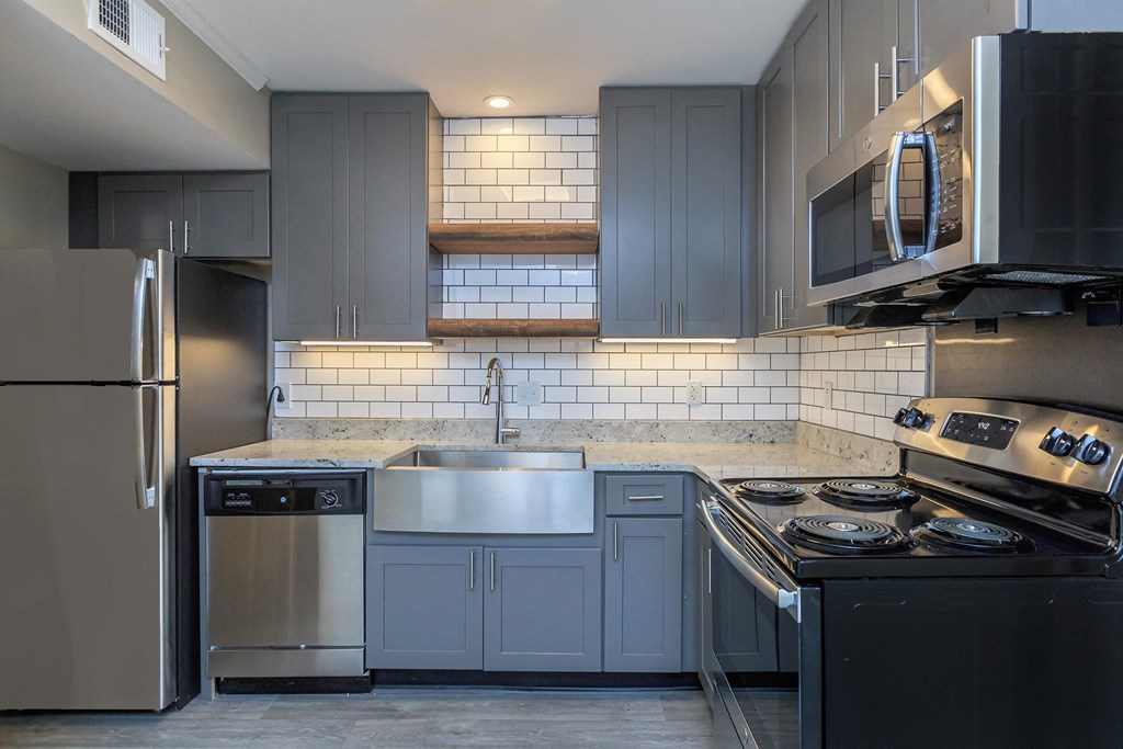 a kitchen with gray cabinets and stainless steel appliances
