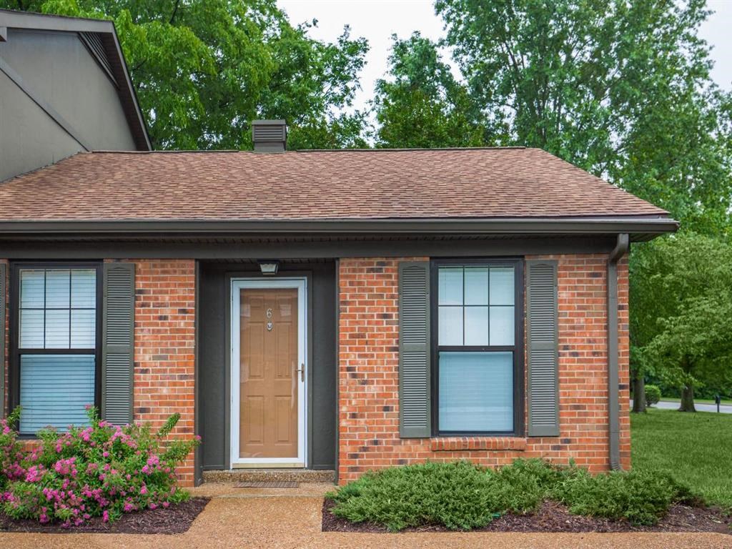the front of a brick house with a brown door