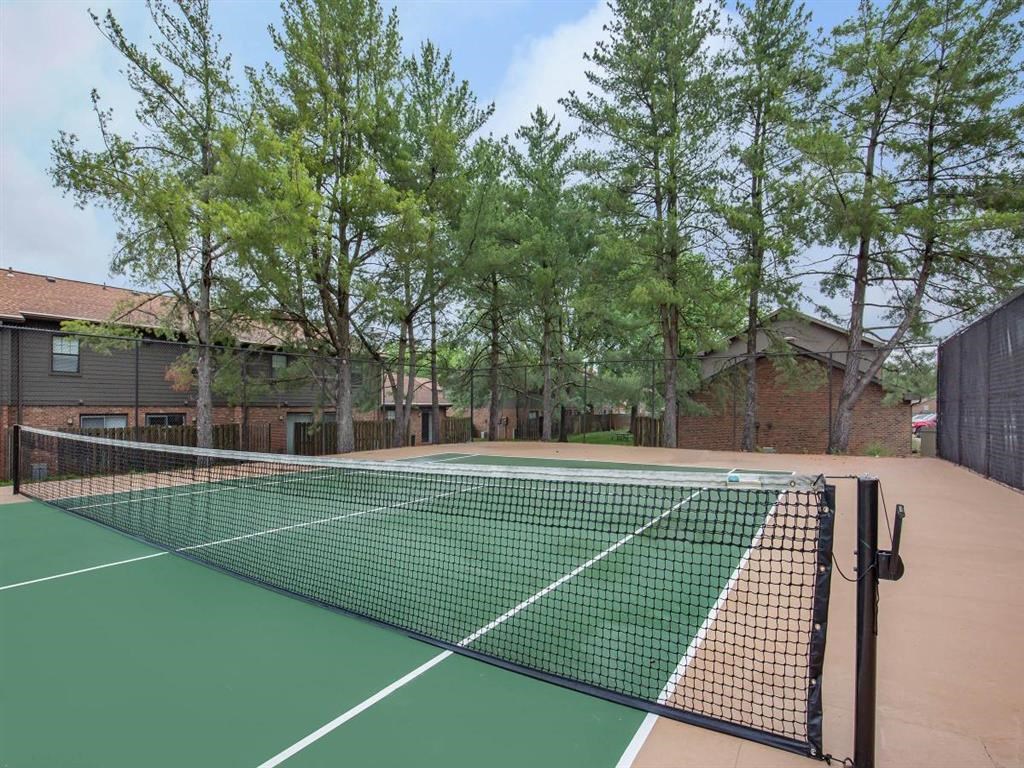 a tennis court with trees and buildings in the background