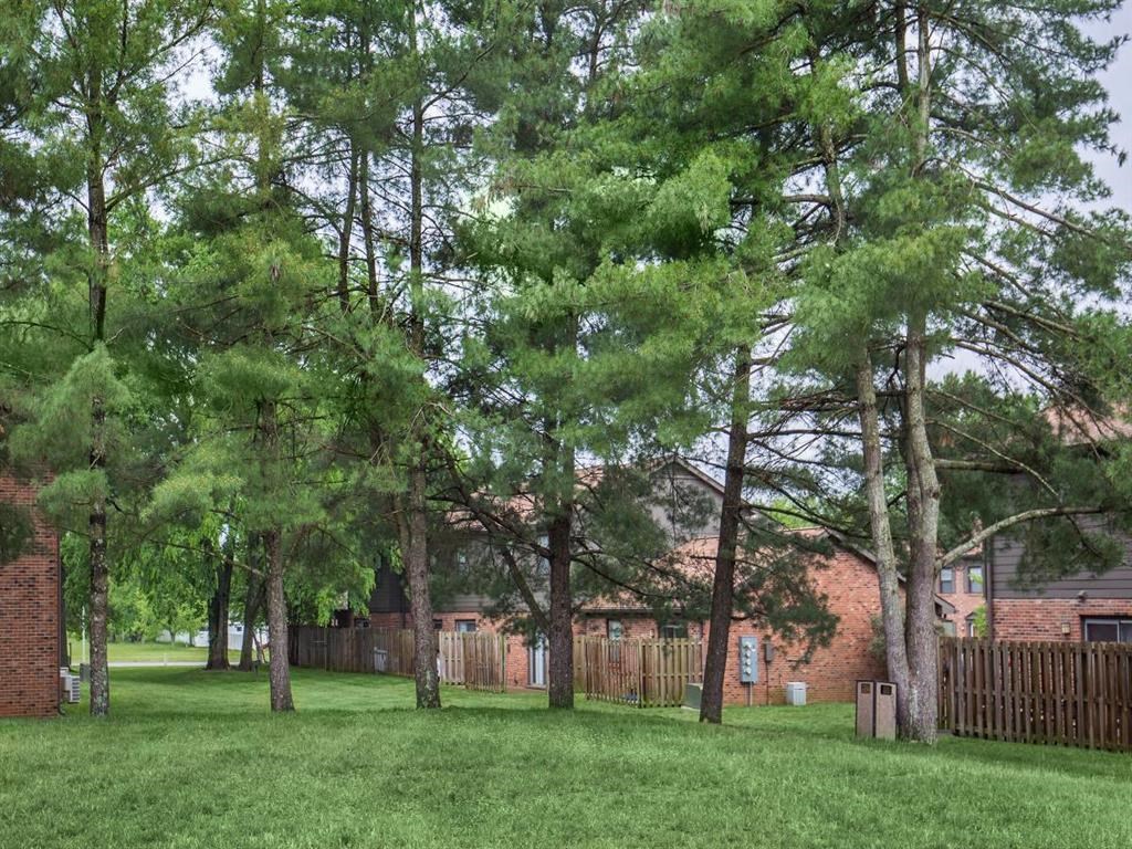 a yard with trees in front of a brick building