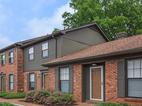 the front of a brick house with a brown door