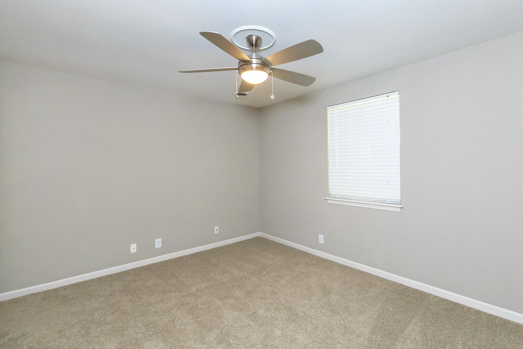 an empty room with a ceiling fan and a window