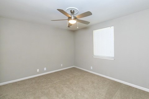 an empty room with a ceiling fan and a window