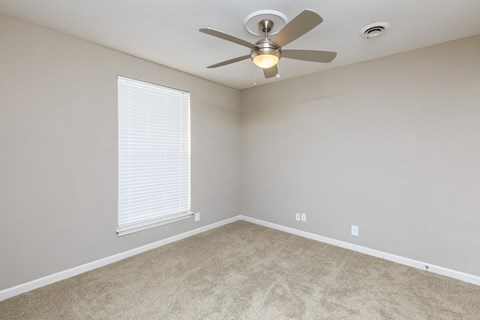 an empty living room with a ceiling fan and a window