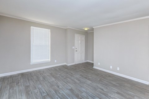 an empty living room with a white door and wood flooring