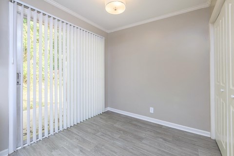 an empty living room with white blinds on the window
