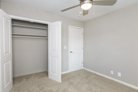 an empty bedroom with a closet and a ceiling fan