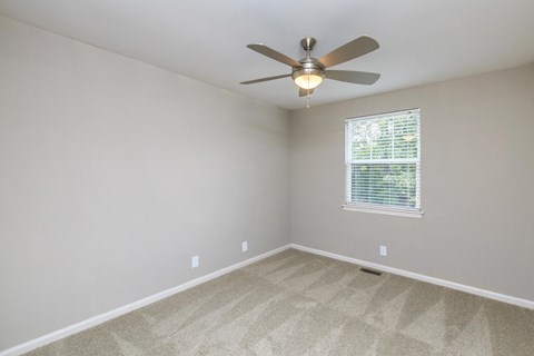 an empty room with a ceiling fan and a window