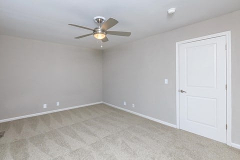an empty room with a ceiling fan and a door
