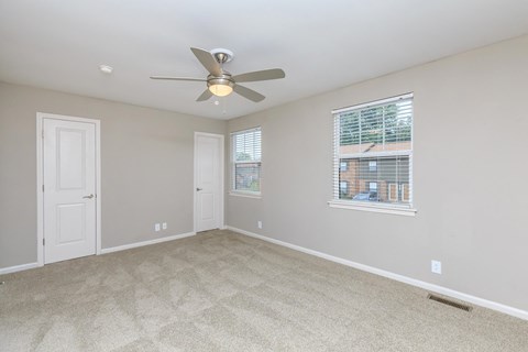 an empty living room with a ceiling fan and a window