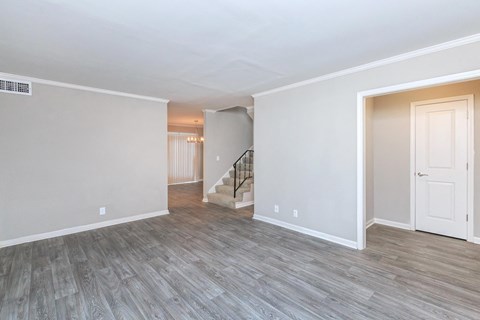 the living room and entryway of a renovated house with wood flooring
