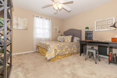 a bedroom with a bed and a desk and a ceiling fan