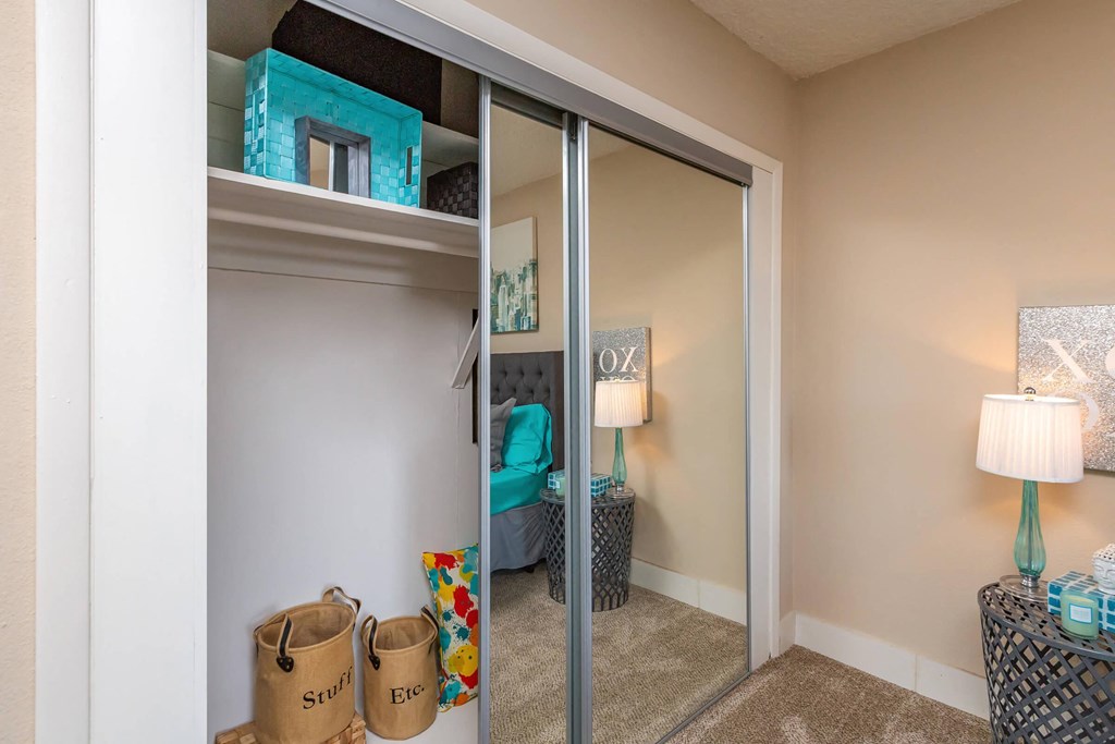a bedroom with a closet and a mirrored closet door