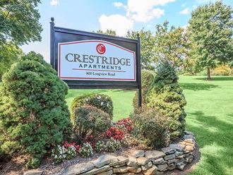 a sign for crestside apartments sits in front of a garden