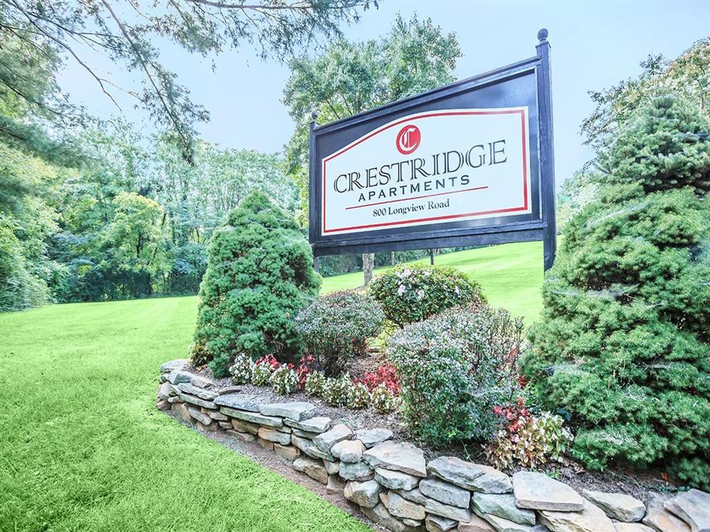 the sign is in front of a stone retaining wall and bushes