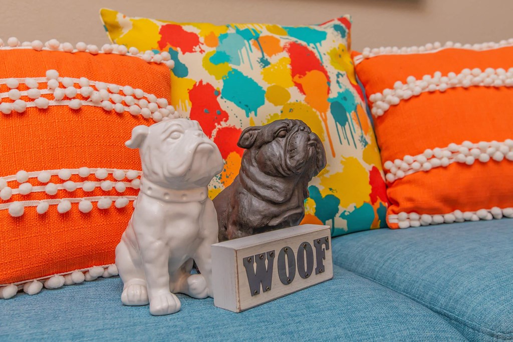 two figurines of dogs sitting on a couch with a wood sign