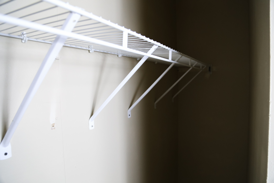 a white closet rack hanging on a wall in a closet