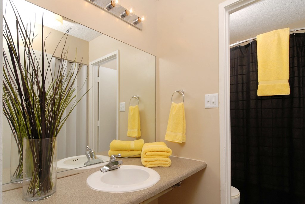 a bathroom with yellow towels and a sink and a mirror
