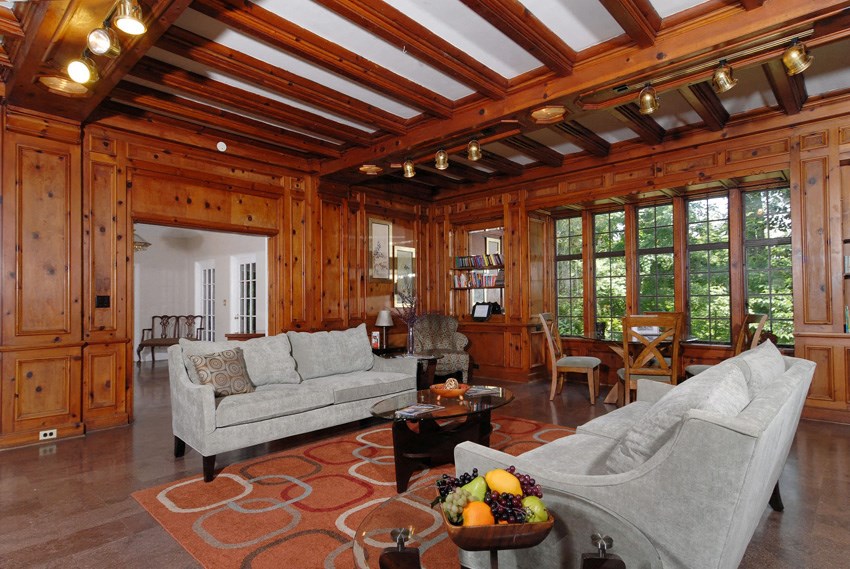 the living room has wood paneled walls and a coffered ceiling