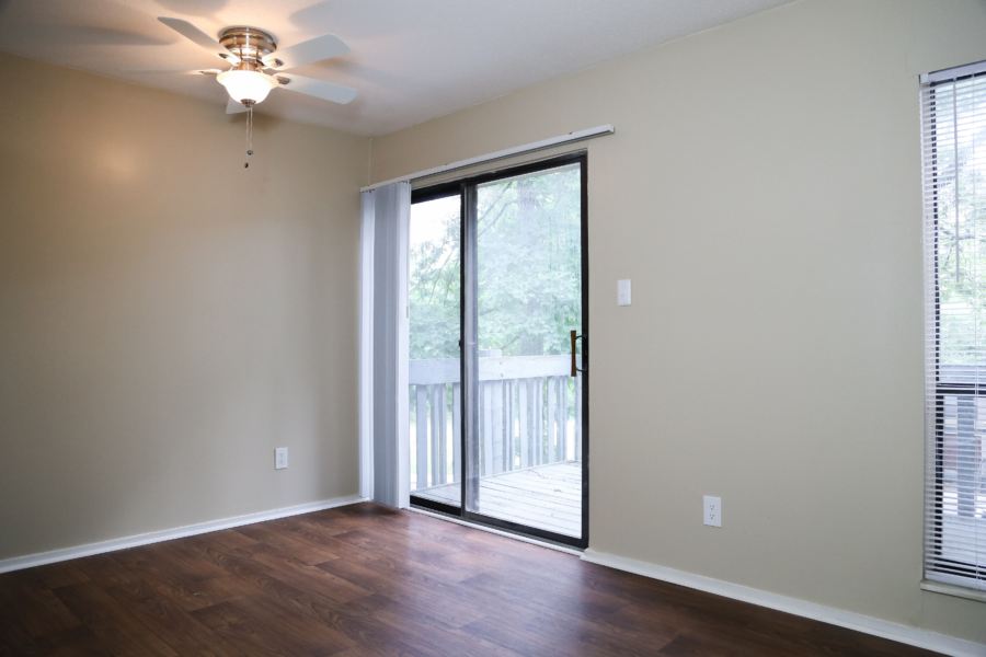an empty living room with a sliding glass door to a balcony