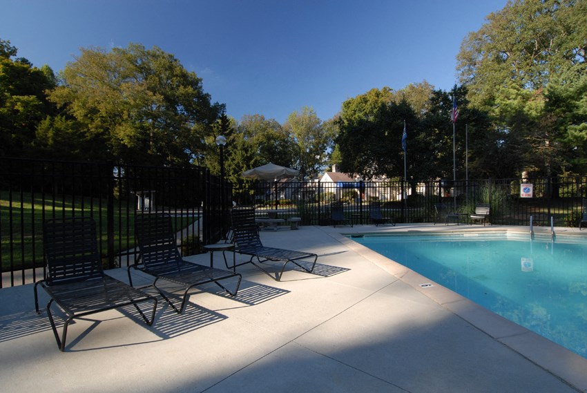 a swimming pool with chairs and a fence around it