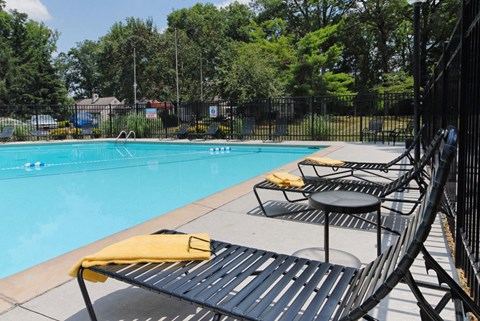a swimming pool with chairs and tables next to it