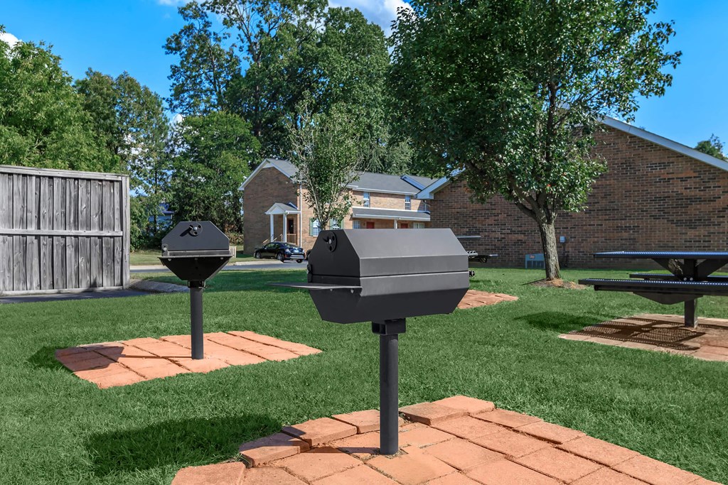 a backyard with two barbecue pits and a picnic table