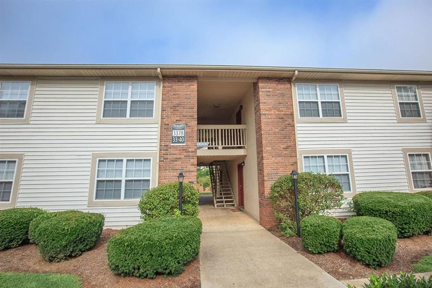 an apartment building with a walkway and manicured bushes