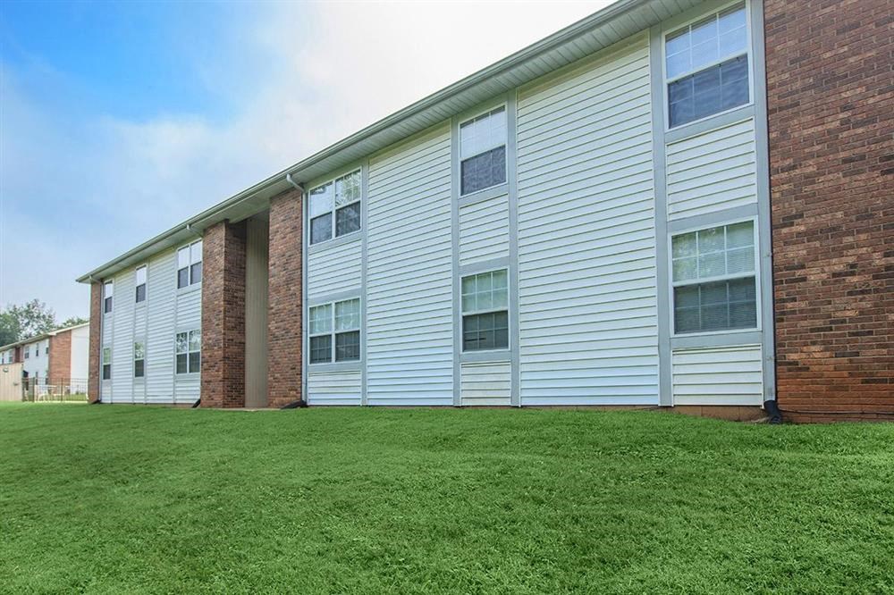 an apartment building with white siding and green grass
