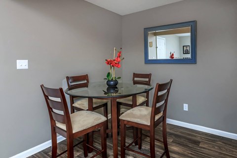a dining room table with four chairs and a mirror