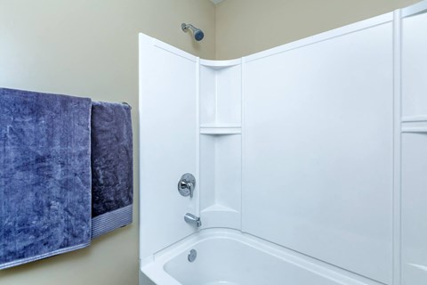 a white bathroom with a tub and a towel rack