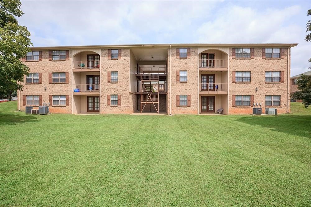 the back of a brick apartment building with a green lawn