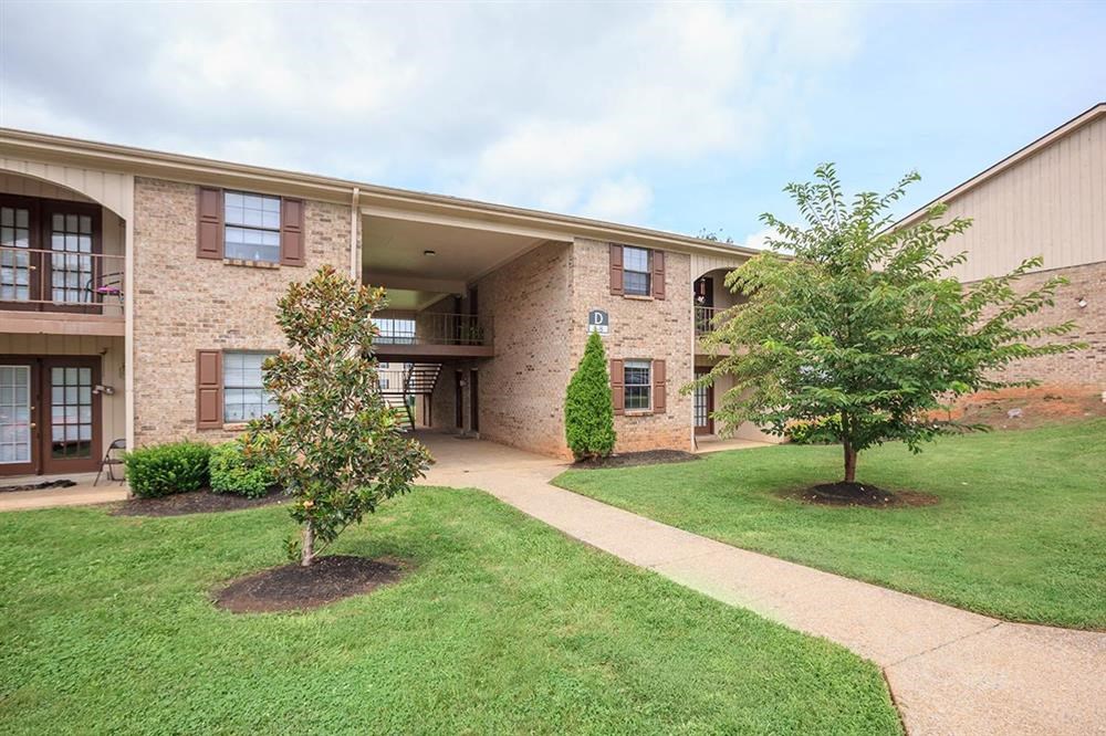 an apartment building with a lawn and trees in front of it