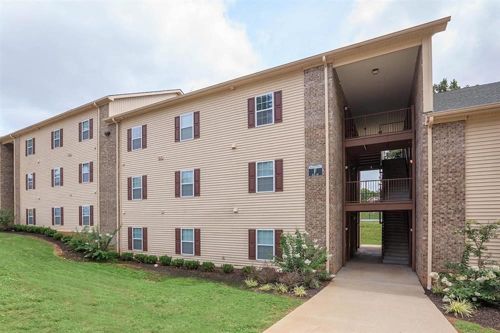 an apartment building with a sidewalk and grass